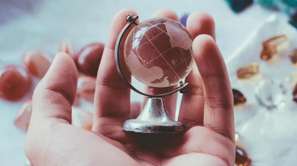 Mano che tiene un piccolo globo di vetro – traduzioni giurate per le autorità di tutto il mondo